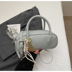 Detailed view of grey lychee leather cylinder bag with colorful woven rope and gold charm
