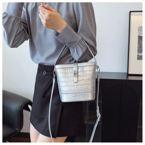 Detailed view of silver crocodile pattern bucket bag worn as a stylish crossbody purse