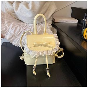 Detalle de mini mochila amarillo claro con ribete de encaje blanco y diseño de lazo dulce