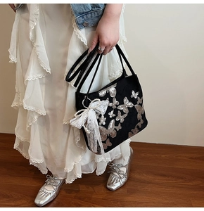 Detail of black tote bag with silver butterfly sequins and lace pearl ribbon accessory