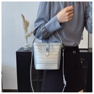 Détail du sac seau argenté à motif crocodile avec fermoir rotatif en métal et double bandoulière
