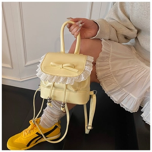 Detalle de la mini mochila amarilla con bordes de encaje blanco y decoración de lazo elegante