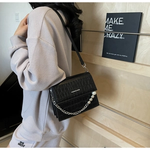 Detail of black faux crocodile leather bag with pearl chain and fashion lettering