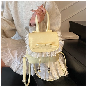 Detalle de mini mochila de charol crema con lazo y ribete de encaje blanco
