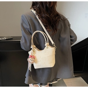 Detail of off-white bucket bag with cartoon embossing and plush doll pendant