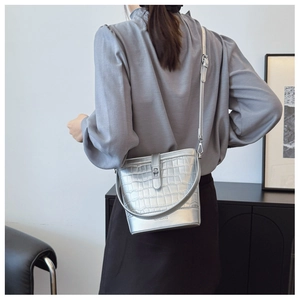 Detail of silver bucket bag featuring faux crocodile texture and metallic lock buckle