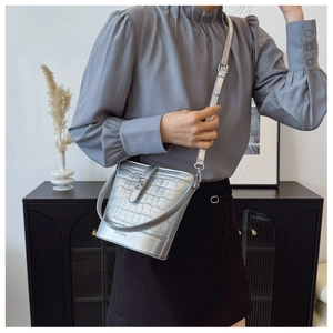 Detailaufnahme der silbernen Beuteltasche mit Krokodilprägung und verstellbaren Trägern