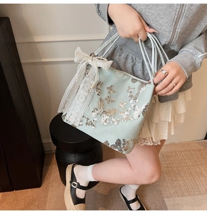 Detail of mint green tote bag with silver sequin butterflies and white lace bow