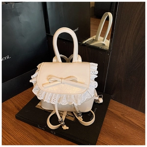 Detalle de una mochila crema con bordes de encaje delicado y decoración de lazo