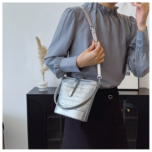 Close-up of silver bucket bag with crocodile texture and adjustable shoulder strap