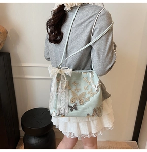 Close-up of butterfly sequin embroidery and lace bow on mint green shoulder bag