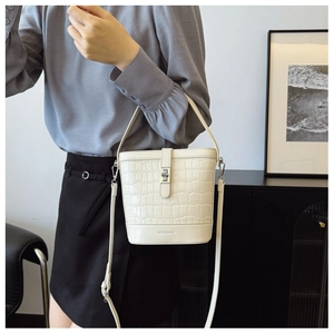 Detail of cream faux crocodile bucket bag featuring silver twist lock and brand logo
