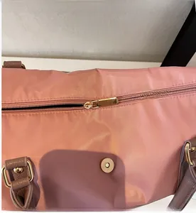 Détail du sac fourre-tout en nylon nacré rose avec zip doré et poignée en cuir marron