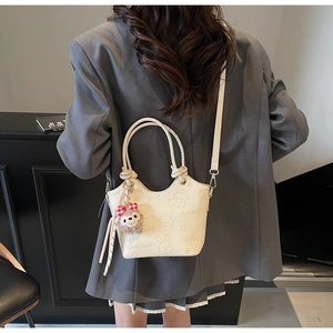 Detail of cream bucket bag with embossed animal patterns and cute plush charm
