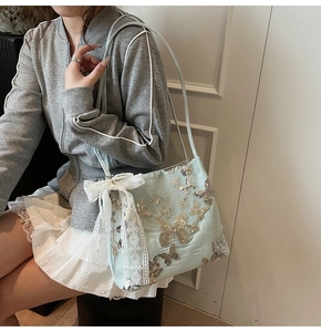 Detail of light blue tote bag featuring silver butterfly sequins and lace pearl bow