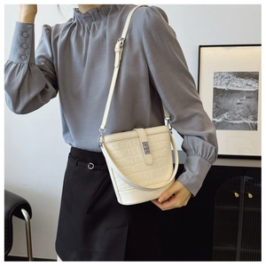 Detail of cream bucket bag showing crocodile embossed leather and silver metal twist lock