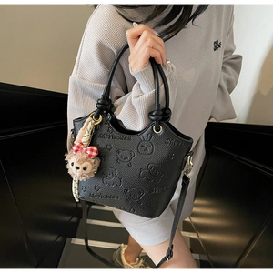 Close-up of black textured leather bucket bag with cute cartoon bear and rabbit embossing