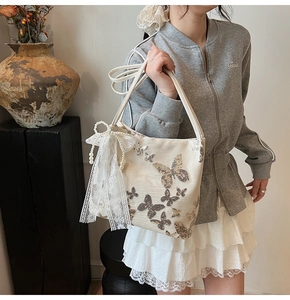 Detail of cream shoulder bag with sequined butterfly embroidery and pearl charms