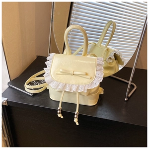 Detalle de mini mochila amarilla con ribete de encaje, lazo y cordón con cuentas