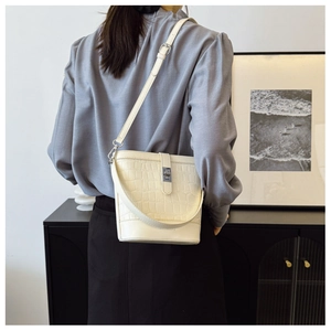 Chic cream crocodile pattern bucket bag shown on model with silver metal twist lock clasp