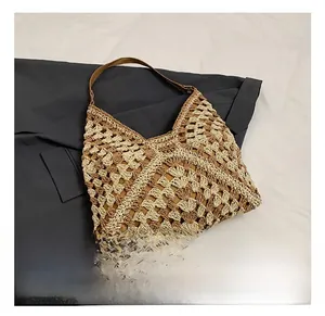 Detail showing two-tone crochet weave pattern and brown leather strap of the shoulder bag