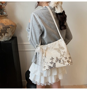 Detail of cream shoulder bag with sequin butterfly embroidery and lace bow with pearls