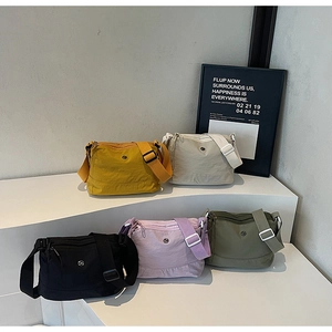 Detailed display of five nylon crossbody bags in yellow beige black purple and green