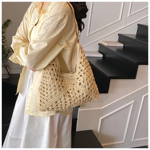 Detail of hollow-out woven straw tote bag featuring contrast colors and crochet texture