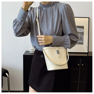 Detail view of a white crocodile embossed bucket bag styled with a modern outfit