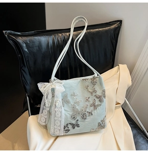 Close-up of light blue handbag featuring sequined butterflies and lace ribbon with pearls