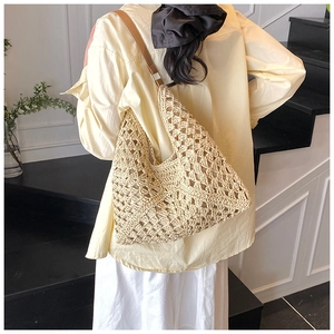Detail of hollow woven beach bag featuring beige crochet texture and brown leather strap