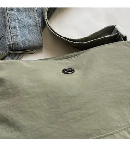 Close-up of grass green canvas crossbody bag with wrinkled texture and round hardware logo