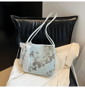 Detail of light blue silk tote bag with silver sequin butterfly embroidery and lace charm
