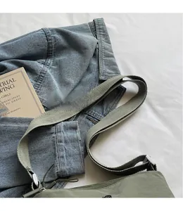 Detail of adjustable wide grey strap on a green lightweight nylon crossbody bag