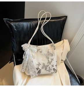Detail view of embroidery butterfly tote bag with lace bow and pearl charm accents