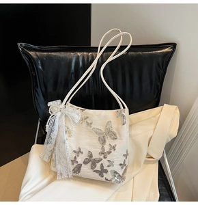 Detail of white fabric tote with silver butterfly embroidery and lace bow accent