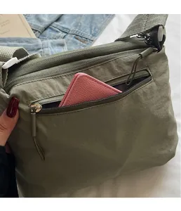 Detail of army green nylon crossbody bag showing multiple pockets and storage capacity