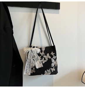 Detail of black tote bag with silver sequin butterflies and delicate lace bow accent