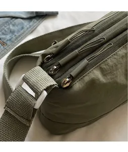 Detail of smooth zippers and durable army green nylon fabric on a crossbody bag