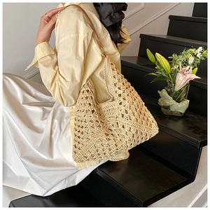Detail of hand-woven crochet hobo bag with hollow diamond pattern and leather strap