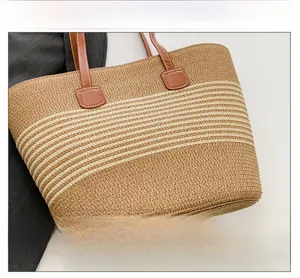 Detail shot of woven straw tote bag with brown leather handles and beige stripe patterns