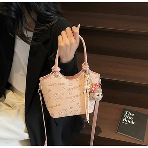 Detailed view of pink bucket bag with cartoon bear print and cute plush animal charm