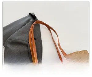 Detail of woven straw tote with contrast leather strap and decorative white stitching