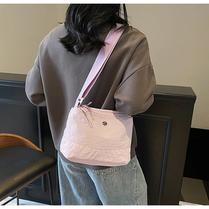Detail of light purple nylon crossbody bag with adjustable wide strap on model