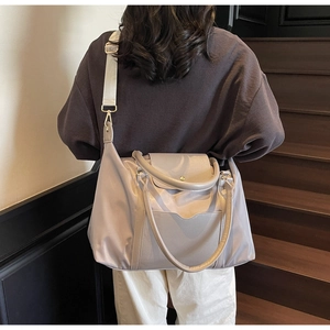 Grand sac fourre-tout gris-violet porté à l'épaule par un mannequin sur un escalier