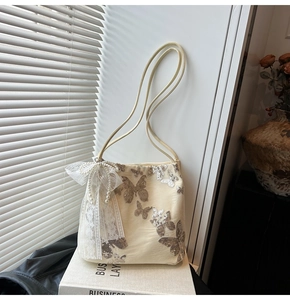 Detail of embroidered silver butterfly and lace bow with pearl charm on cream tote