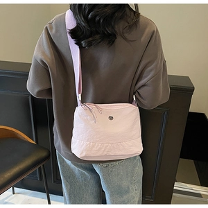 Back view of a casual lavender canvas crossbody bag worn with denim and wide strap
