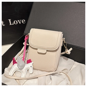 Détail d'un sac à bandoulière en cuir beige avec charm cheval sur doublure soie