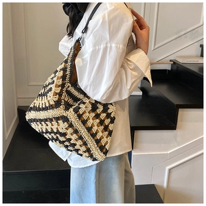 Detail of handwoven checkered tote bag with black leather shoulder strap and large capacity