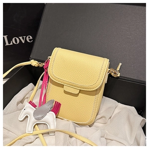 Détail du mini sac bandoulière jaune en cuir grainé avec charm cheval dans son coffret